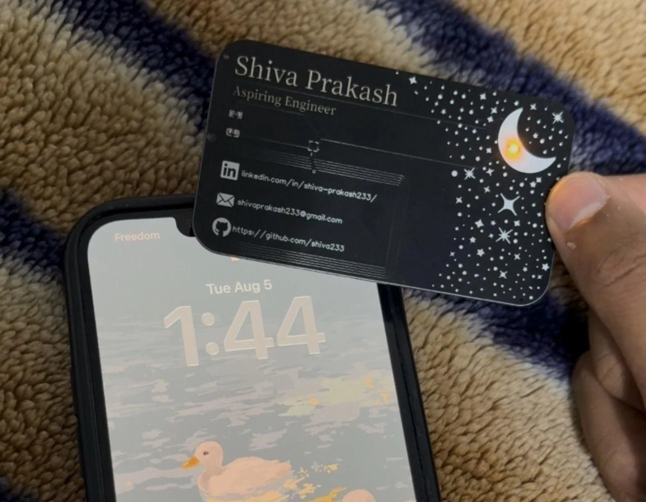 Shiva's physical NFC business card lighting up above a smartphone